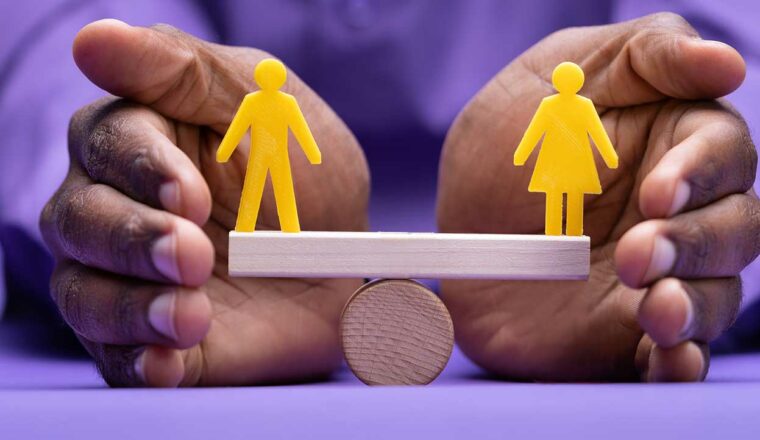 Hands protecting a see saw with a male and female icon balanced