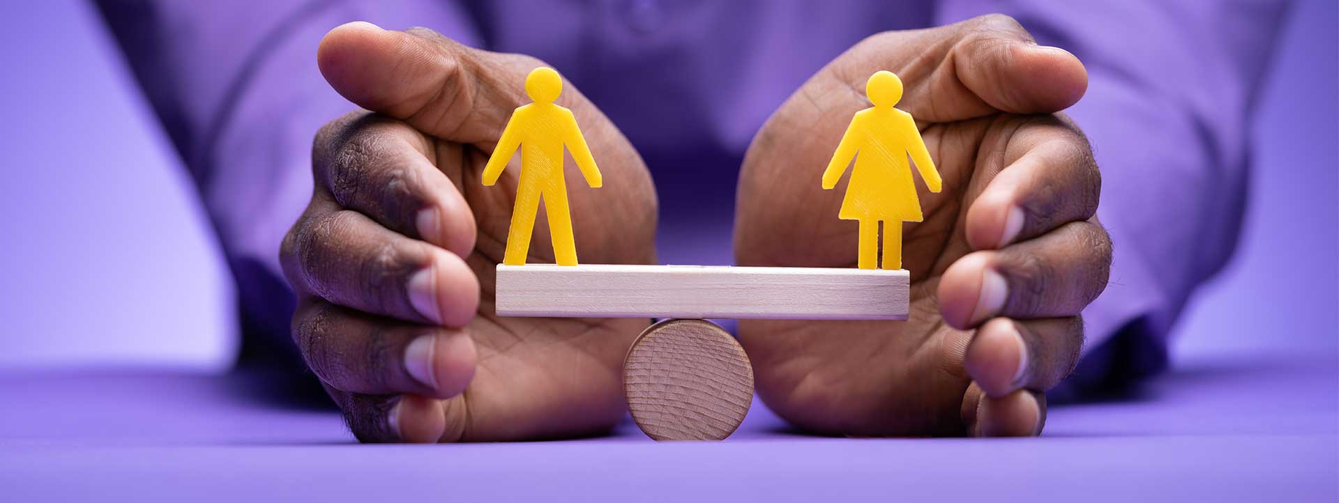 Hands protecting a see saw with a male and female icon balanced
